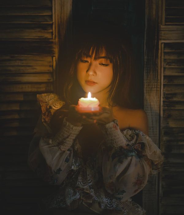 Calm woman meditating in a dark room with soft amber light.